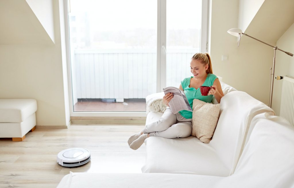 happy woman and robot vacuum cleaner at home